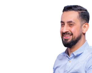 Headshot of Mehmet Yıldız, a Turkish speaker and digital content creator, smiling broadly in a light blue striped shirt, on a transparent background.